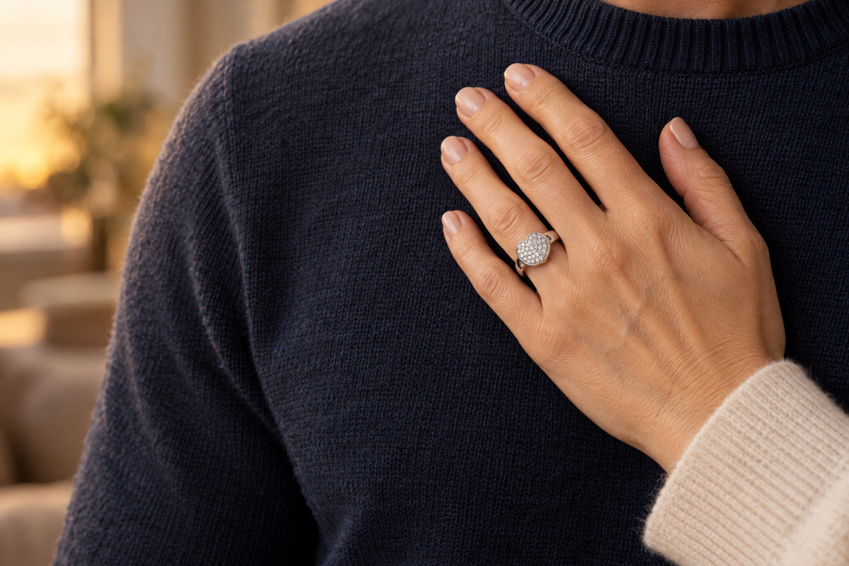 Frauenhand mit Herzring aus Silber und Zirkonia liegt auf der Brust ihres Partners im dunkelblauen Pullover